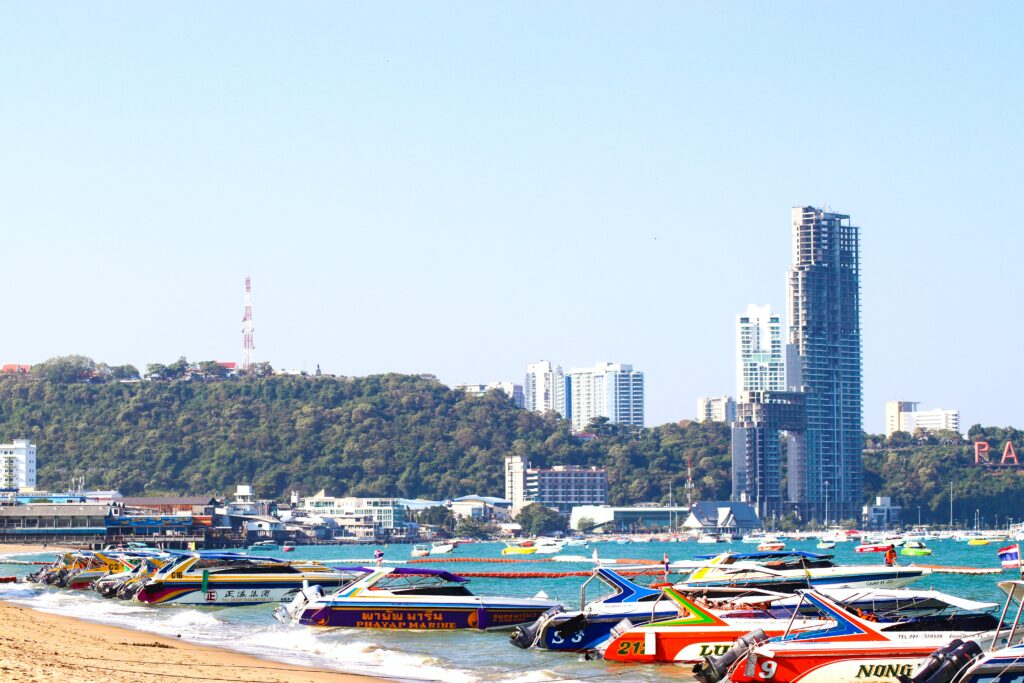 several boats along Pattaya Beach and many high rise buildings in the distance, is Pattaya expensive to visit