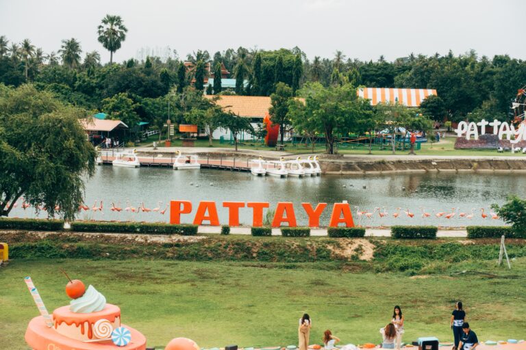 tourist walking around a greenery area at a park with the Pattaya sign by the river in the background / how to get around Pattaya City