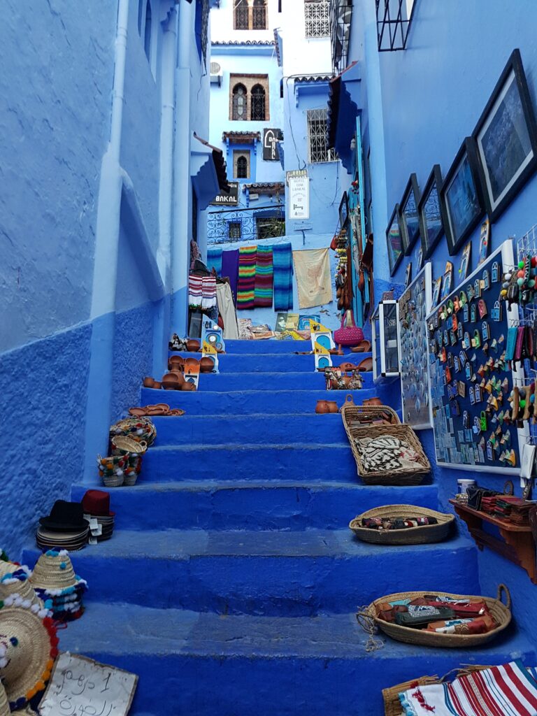 beautiful blue painted walls and stairway path along with many items on the side of the pathway in Chefchaeoun, Morocco