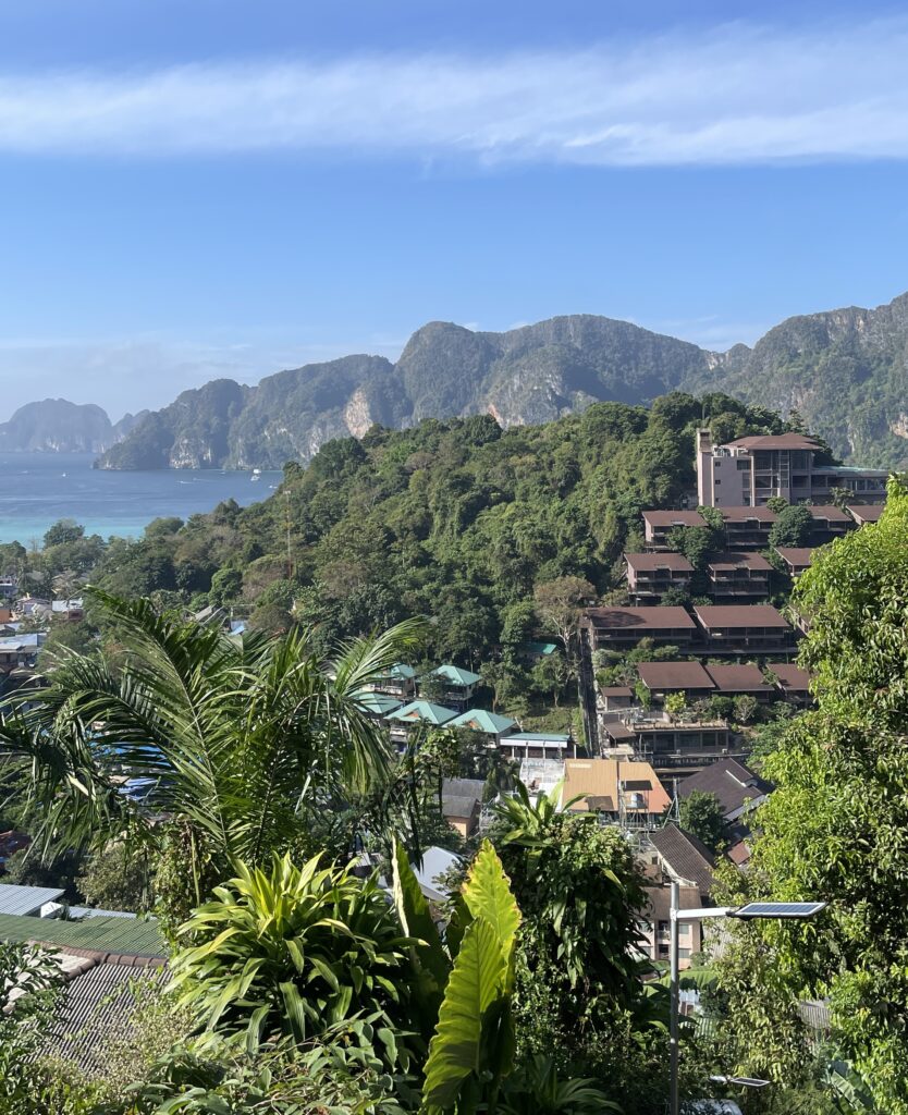 several hotels located amongst the hills of Phi Phi Don with stunning views of the islands bays and large limestones in the distance 