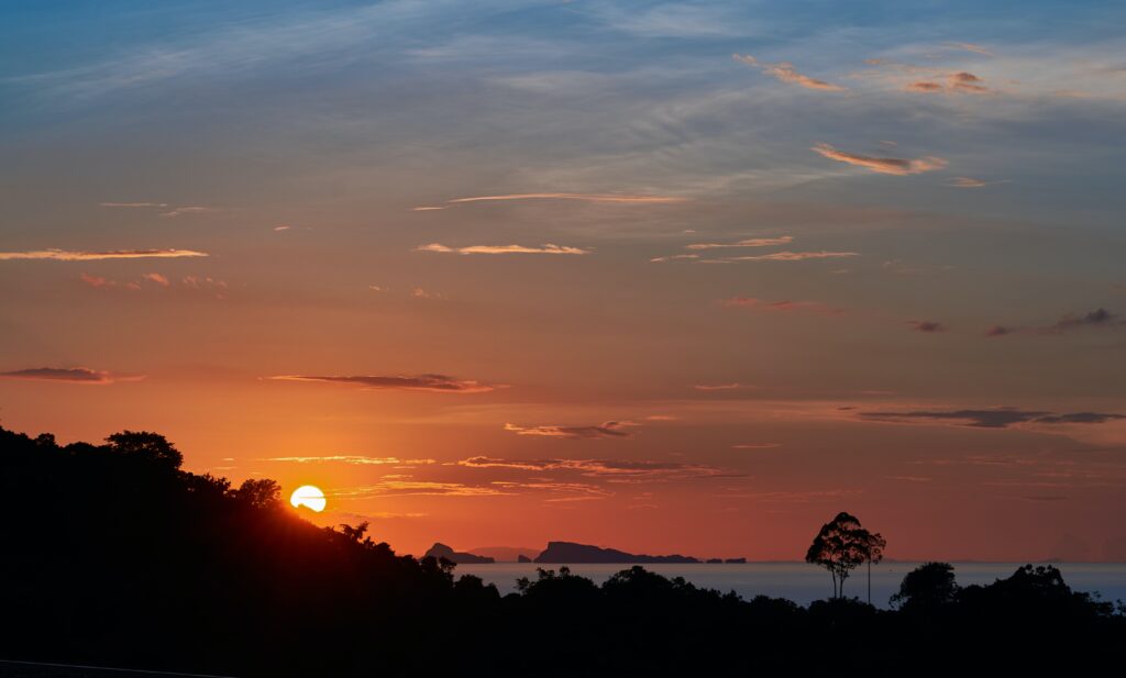 vibrant orange sunset setting from a hill top on Koh Samui, Thailand