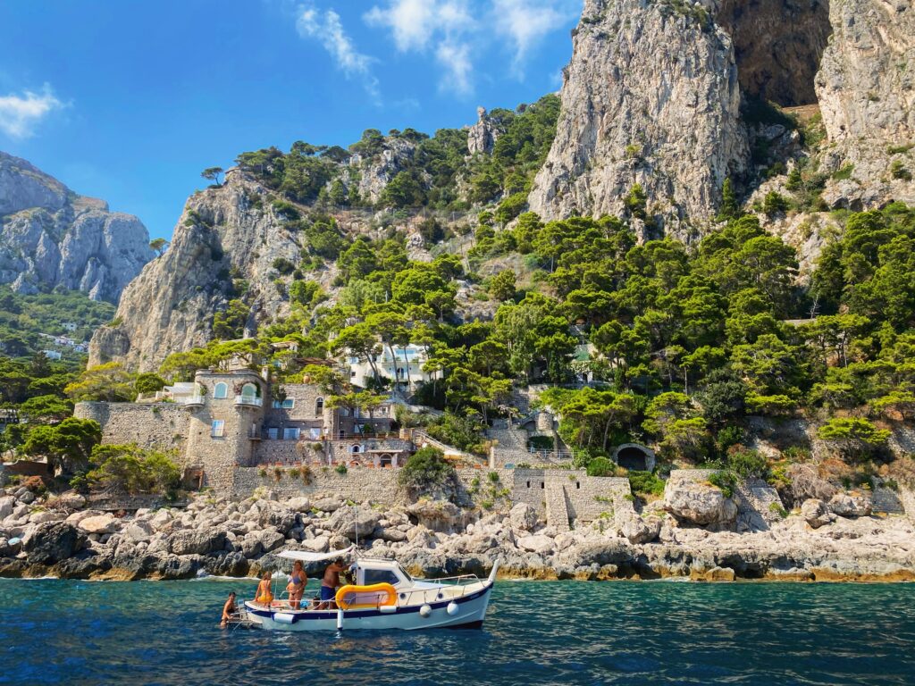 boat sailing by along the sea with stunning large green mountainous hills in the background in Capri, Italy