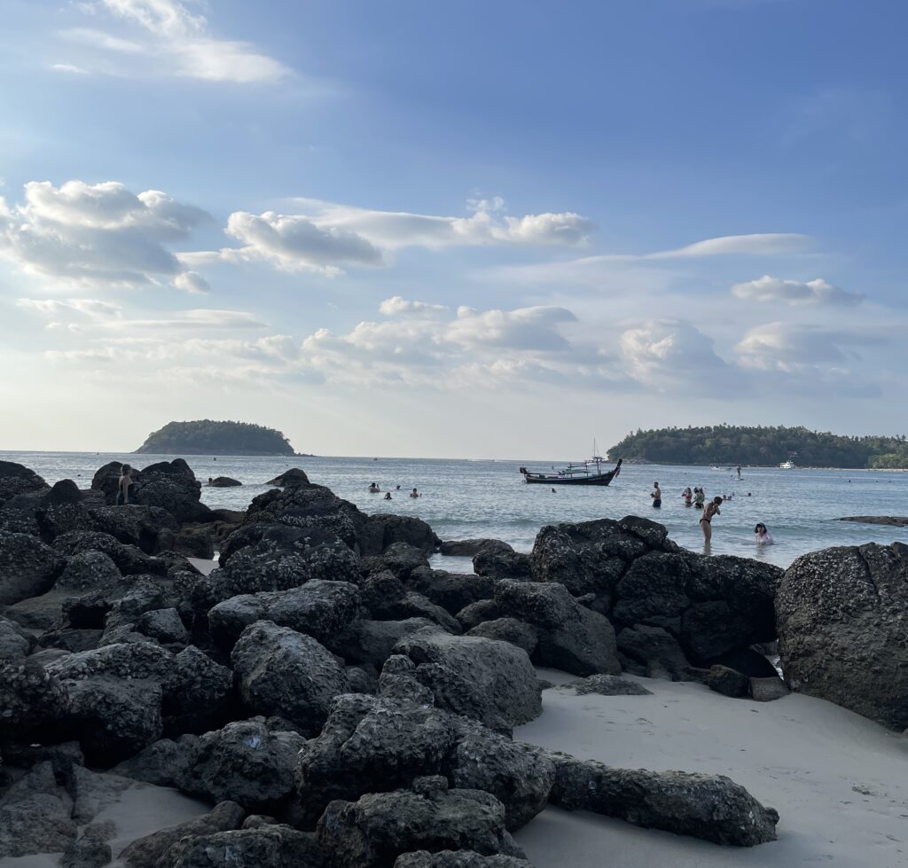 large rocks on the shoreline of Kata Beach with the ocean in the distance