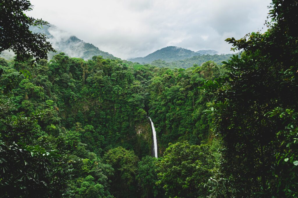 aerial views of the La Fortuna Waterfall surrounded by luscious green jungle and mountains in Costa Rica