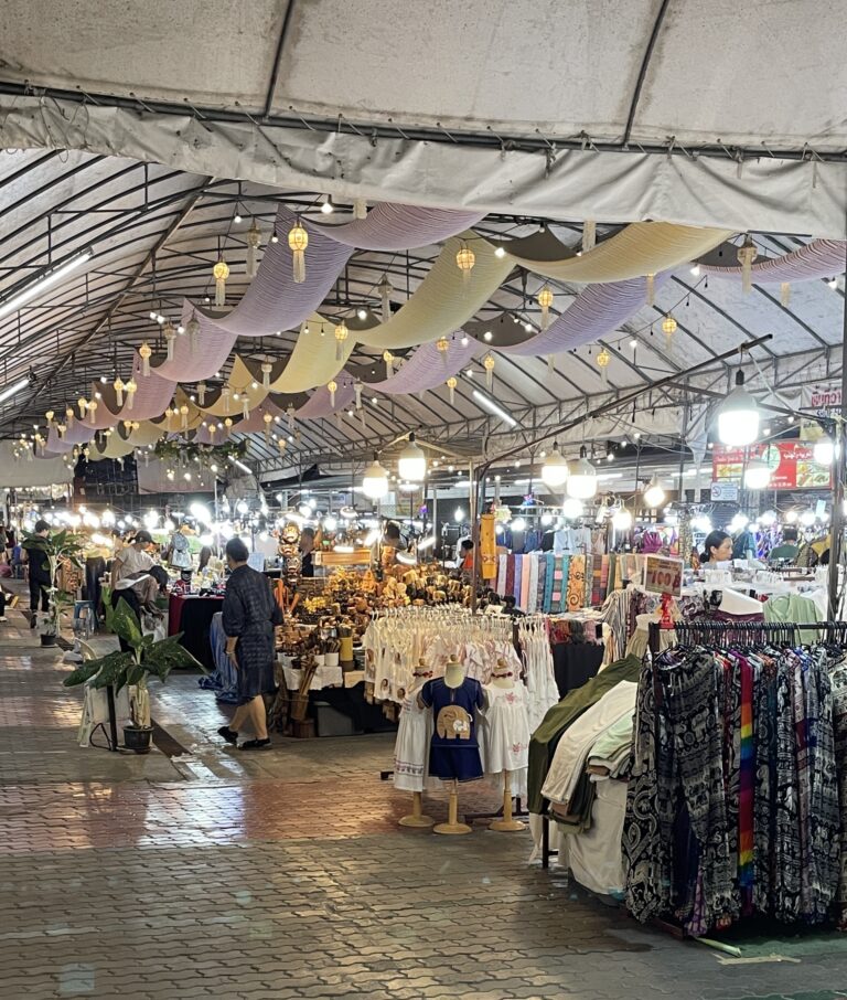 several clothing vendors selling at their stalls and foods in the distance at the Chiang Mai Night Bazaar