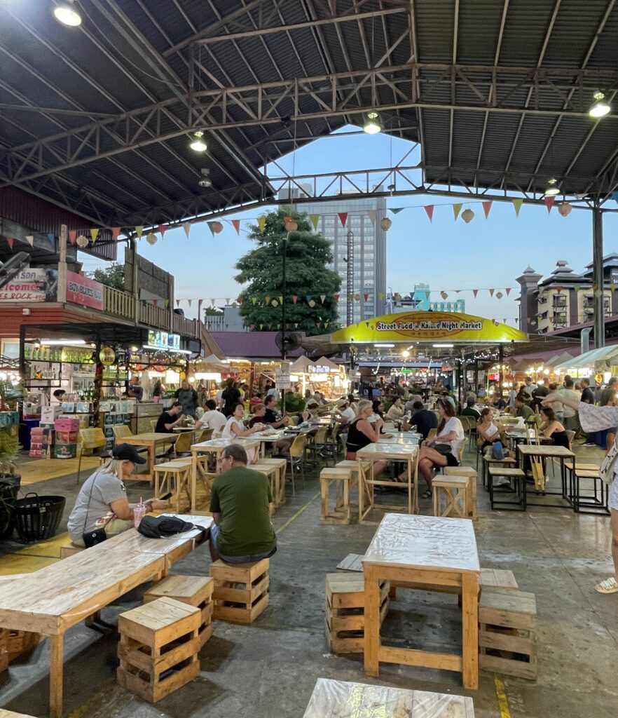 several locals and tourists sitting eating at a popular night market in Chiang MAi