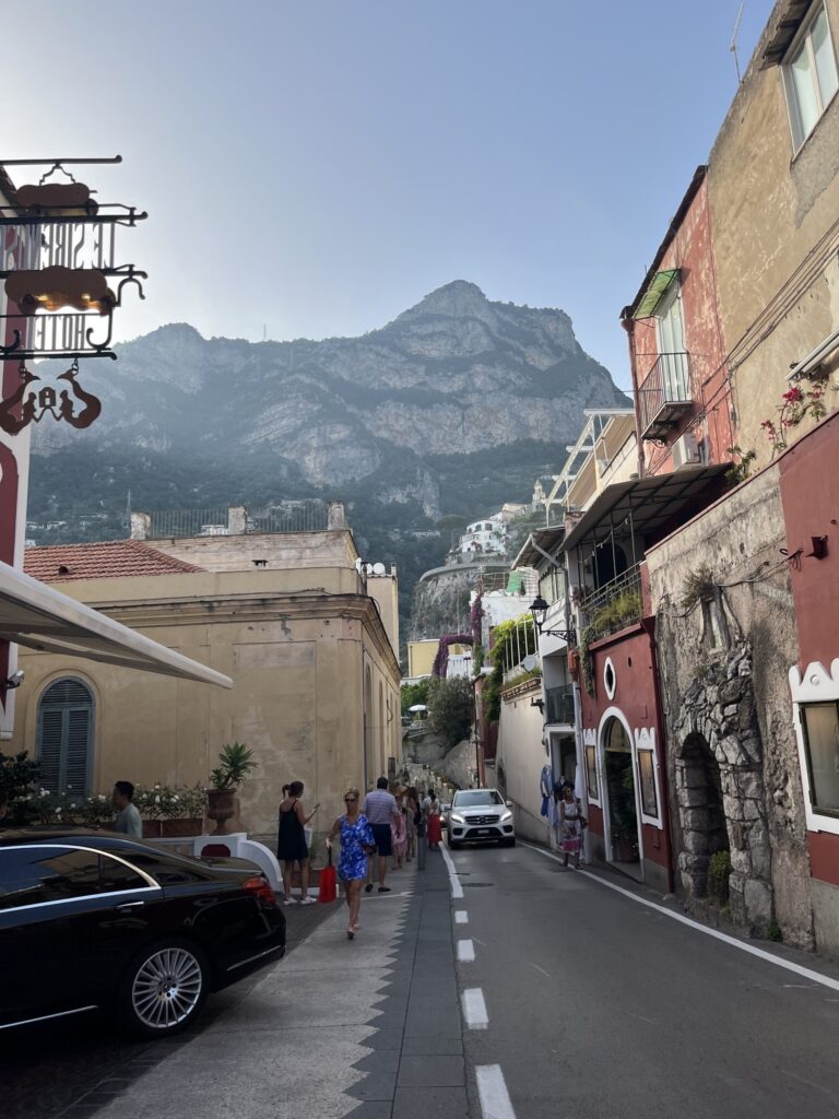 palette coloured buildings, mountains in the distance on picturesque street in Positano, Italy