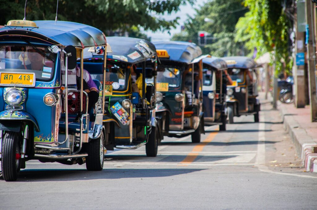 several tuk tuk drivers driving their tuk tuks in Chiang Mai