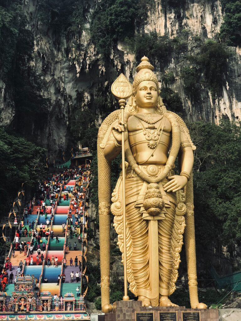 several tourists hiking up the many colourful stairs at the famous Batu Caves, Hindu shrine in Kuala Lumpur, Malaysia