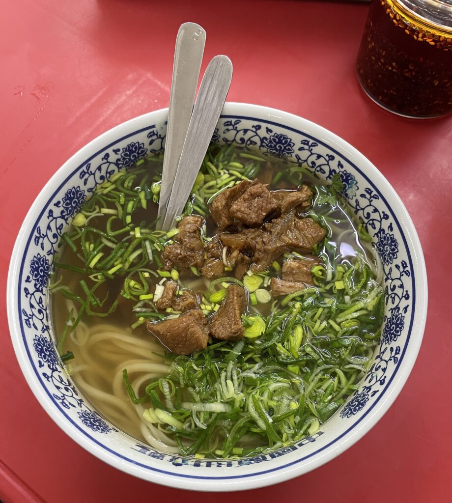 beef ramen noodle dish served with plenty of flavourful herbs 