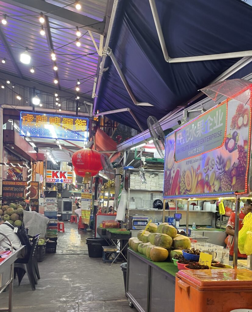 fresh coconuts and other fruits being sold by vendors at the Jalan Alor Night Market in Kuala Lumpur 