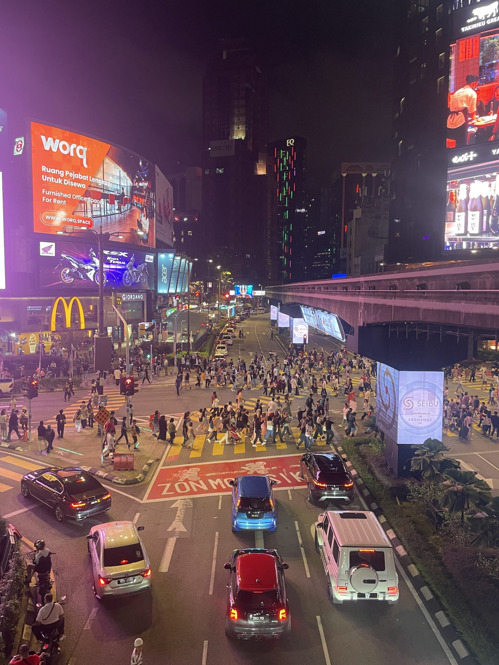 several tourists crossing the at the busiest crosswalk in Kuala Lumpur at night / is Kuala Lumpur safe at night