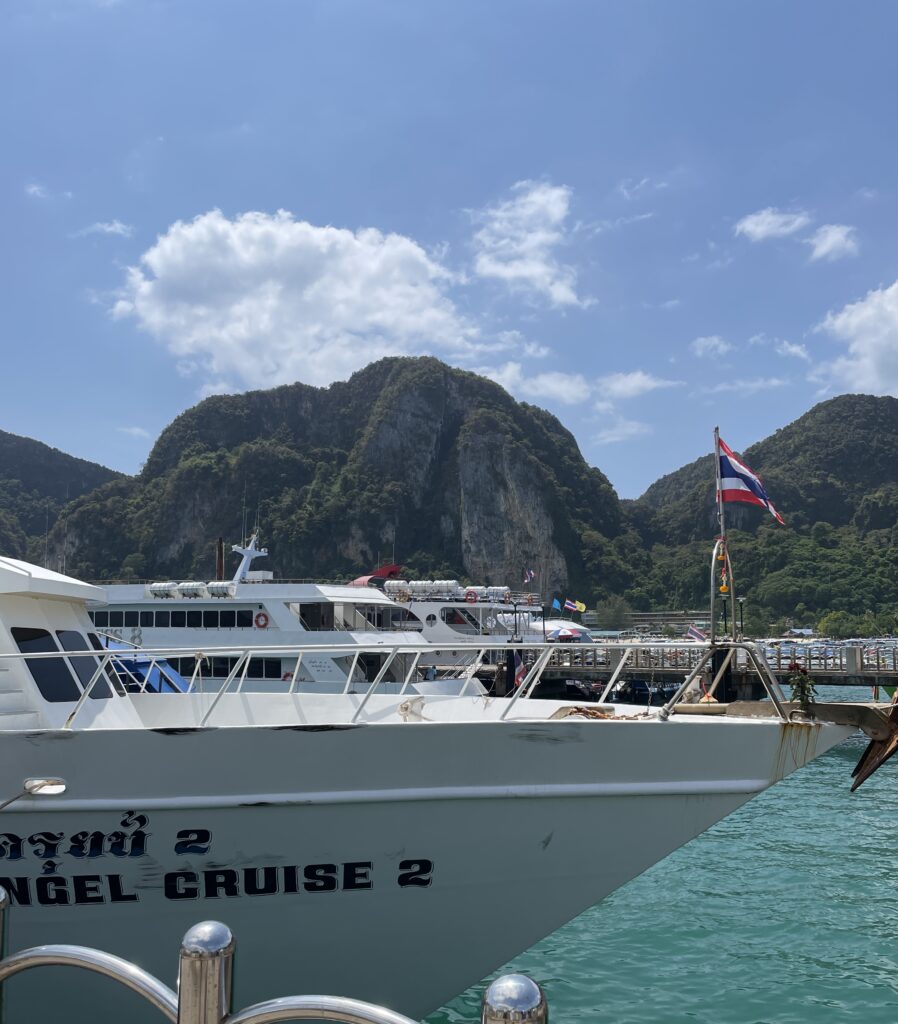 a large ferry docked at Ton Sai Pier in Koh Phi Phi on a clear sky day with large limestones in the background