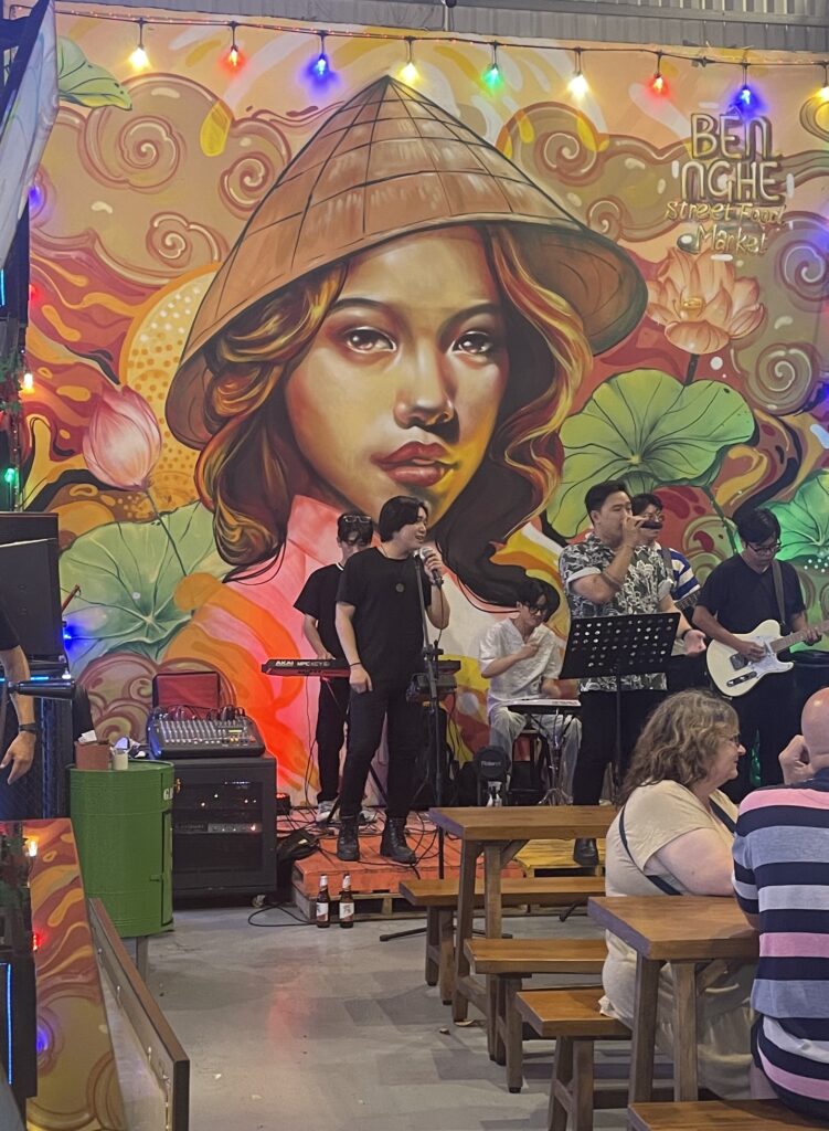 live band performing songs at the Ben Nghe Food Street Market for a crowd dining 