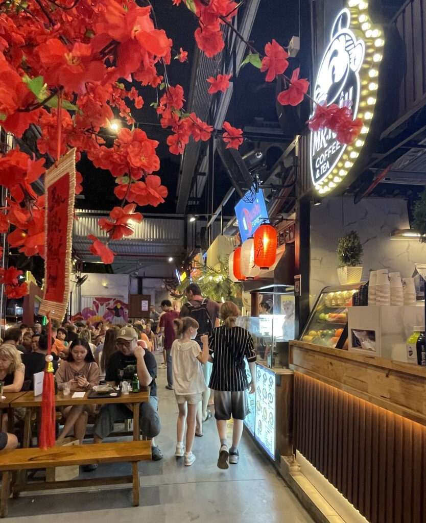 several tourists dining and some walking around the popular Ben Nghe Night Market in Ho Chi Minh City 