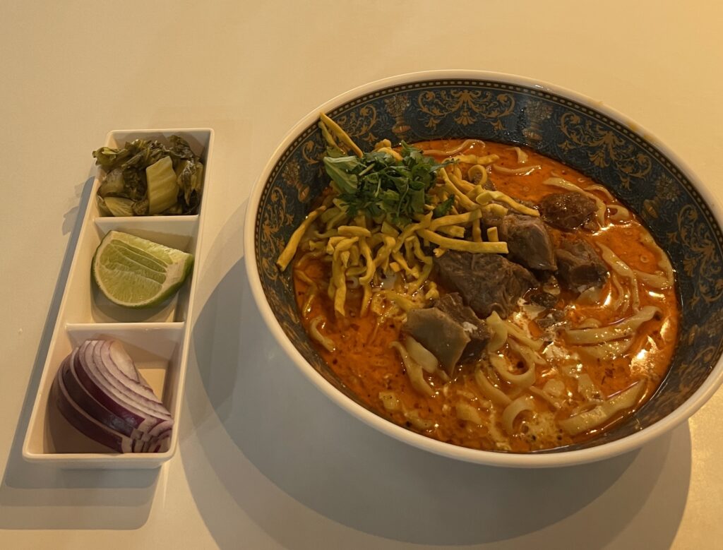 Khao Soi served with onions, and lime at khao Soi doi nang in Chiang Mai / best cheap eats in Chiang Mai