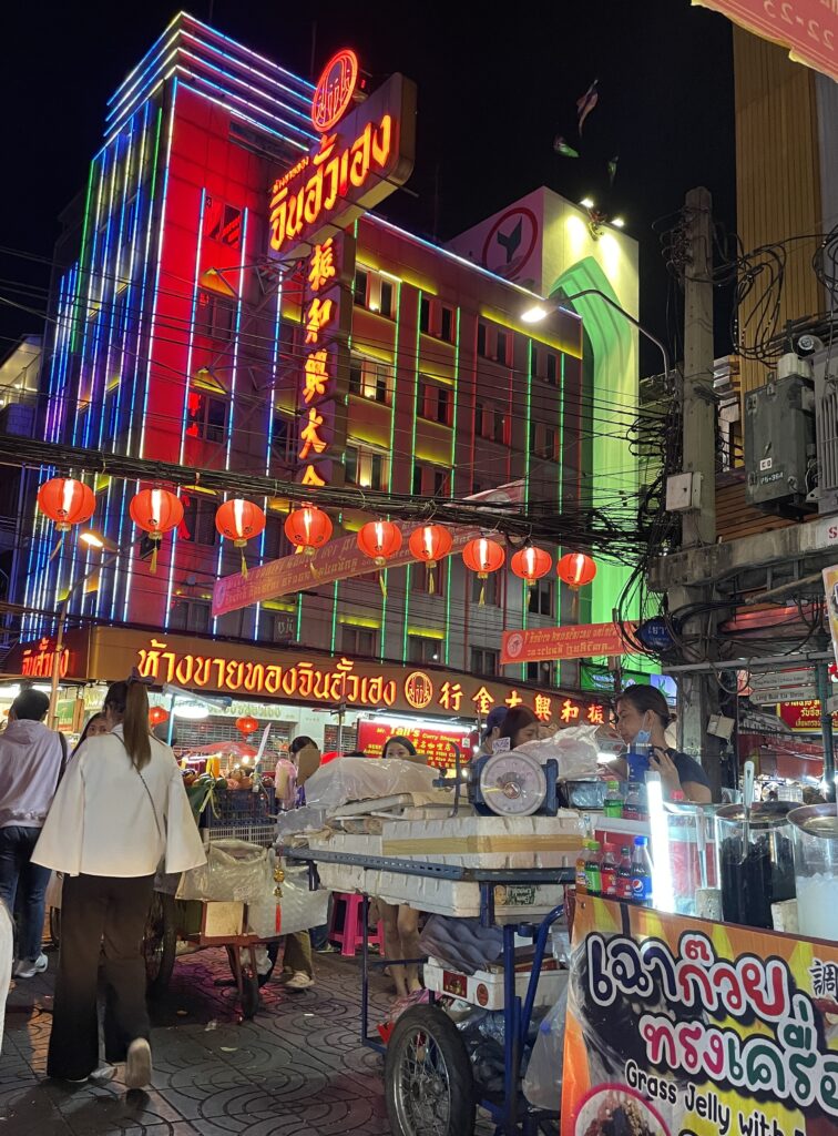 street vendors and tourist dining on street eats amongst many bright lights in the vibrant Chinatown in Bangkok