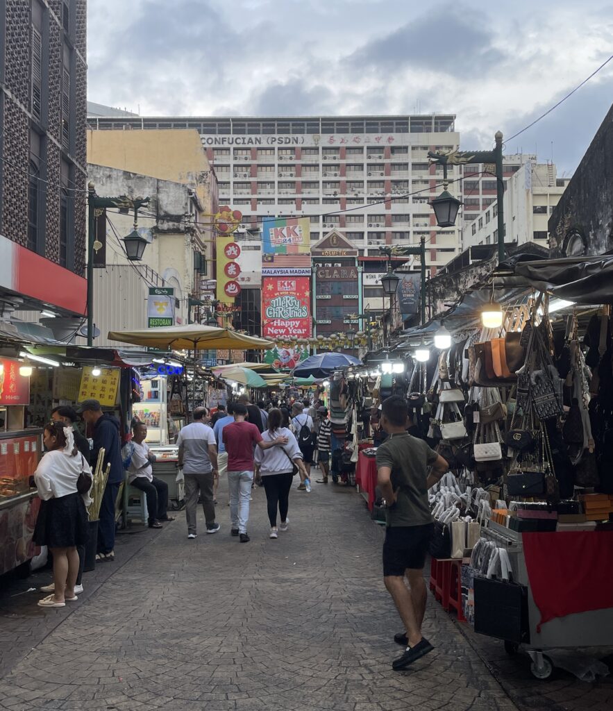 bustling street full of shops and hawker stands selling food in Chinatown, Kuala Lumpur 