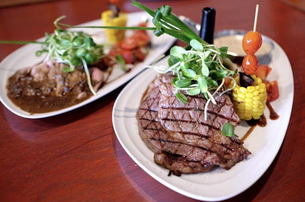 two platted wagyu steaks with some greens at Eat Bar & Grill in Kata Beach