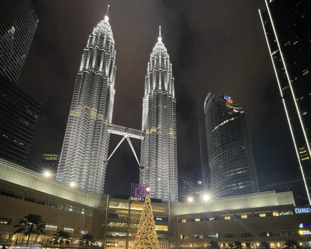 the Petronas Towers in Kuala Lumpur at night amongst many tall towers surroundings it / Is Kuala Lumpur worth visiting