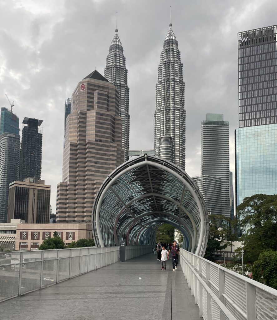 locals crossing the popular Solama link bridge in Kuala Lumpur with the cities skyline in the background featuring the famous Petronas Towers in Kuala Lumpur 