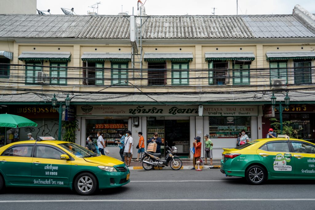 two green and yellow taxis driving by in Thailand 