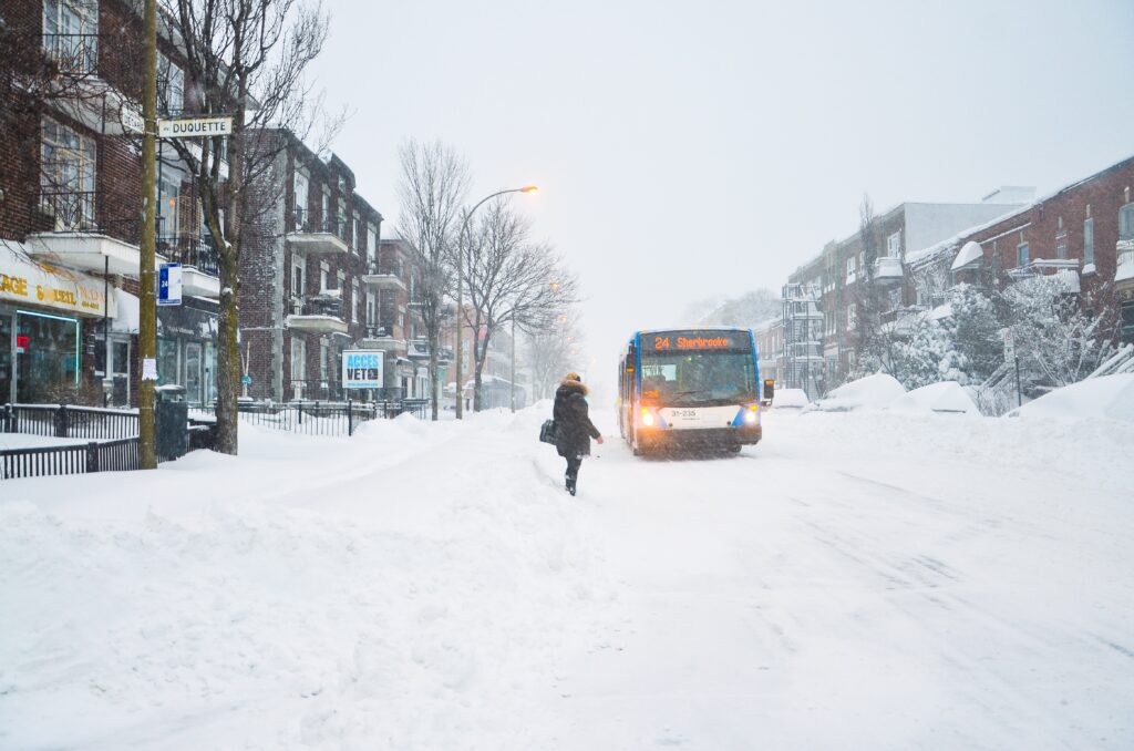 a woman standing on the road waiting for a bus during a heavy snowfall occurred after a snowstorm in Montreal, Canada 