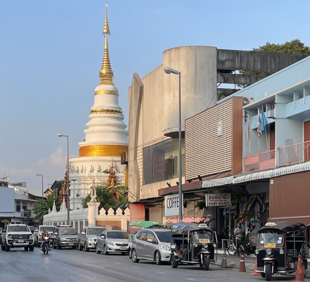 sunset setting in on a popular street in Chiang Mai amongst a temple, and many cars driving by / Chiang Mai Itinerary 4 days