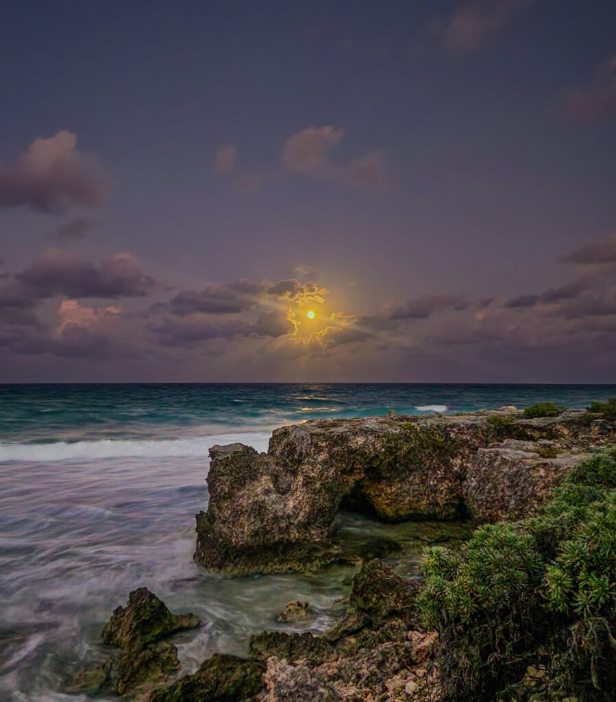 a vibrant sky with a bright full moon over the shorelines of Isla Mujeres, Mexico 