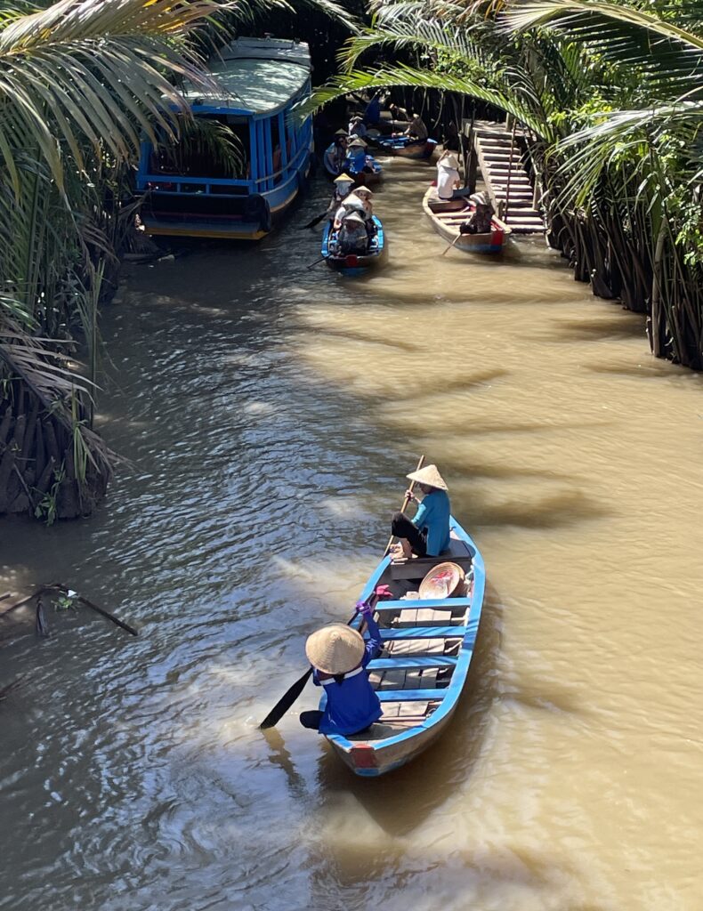 two local ladies rowing through the Mekong Delta River on a sunny day in Vietnam