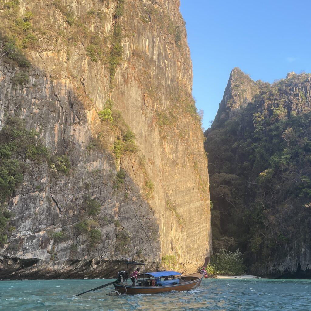 a local Thai man navigating his Thai longtail boat near Pi Leh Lagoon in Krabi, nearby Koh Phi Phi
