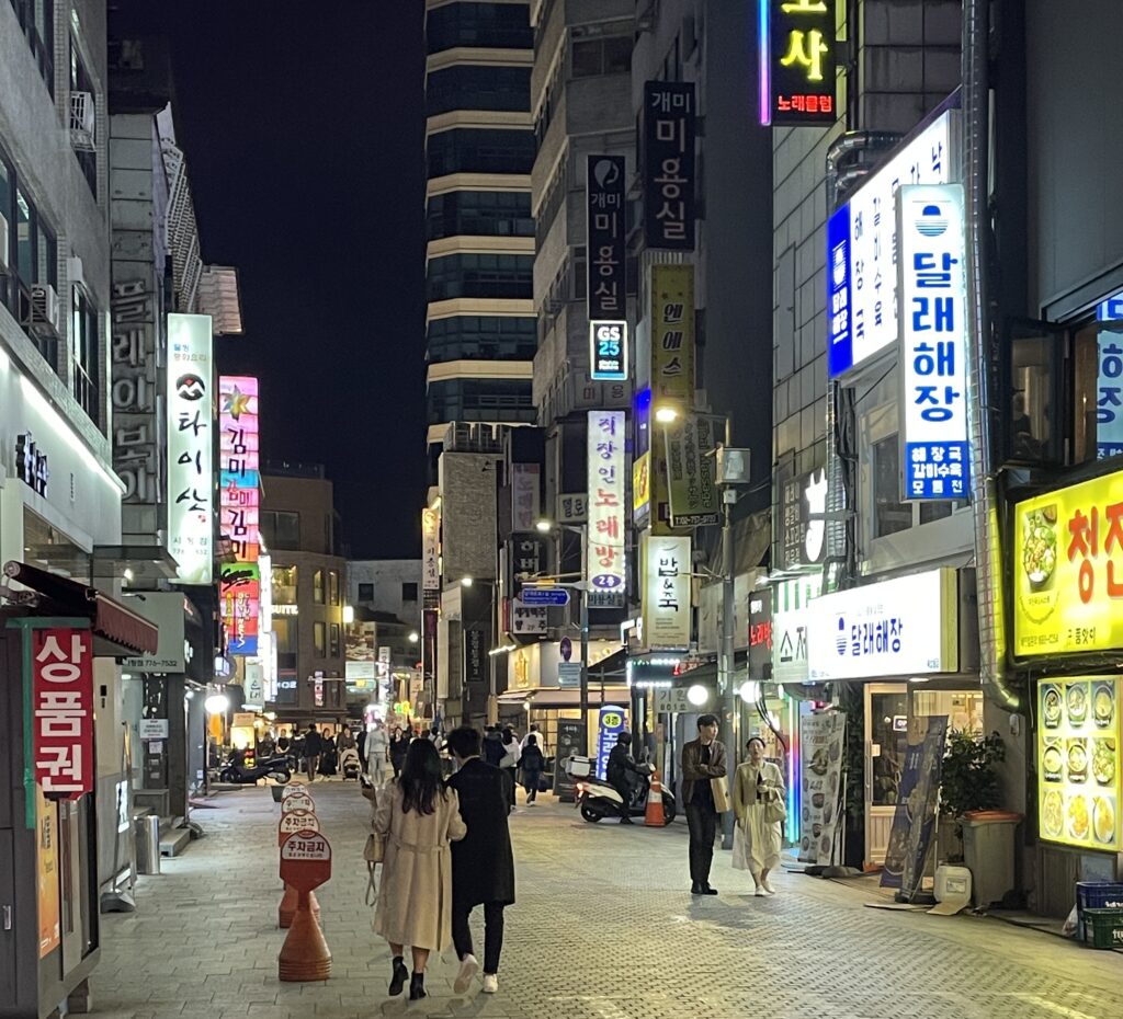 locals in Seoul walking at night on a street with plenty of lit up signs / Seoul itinerary 3 days