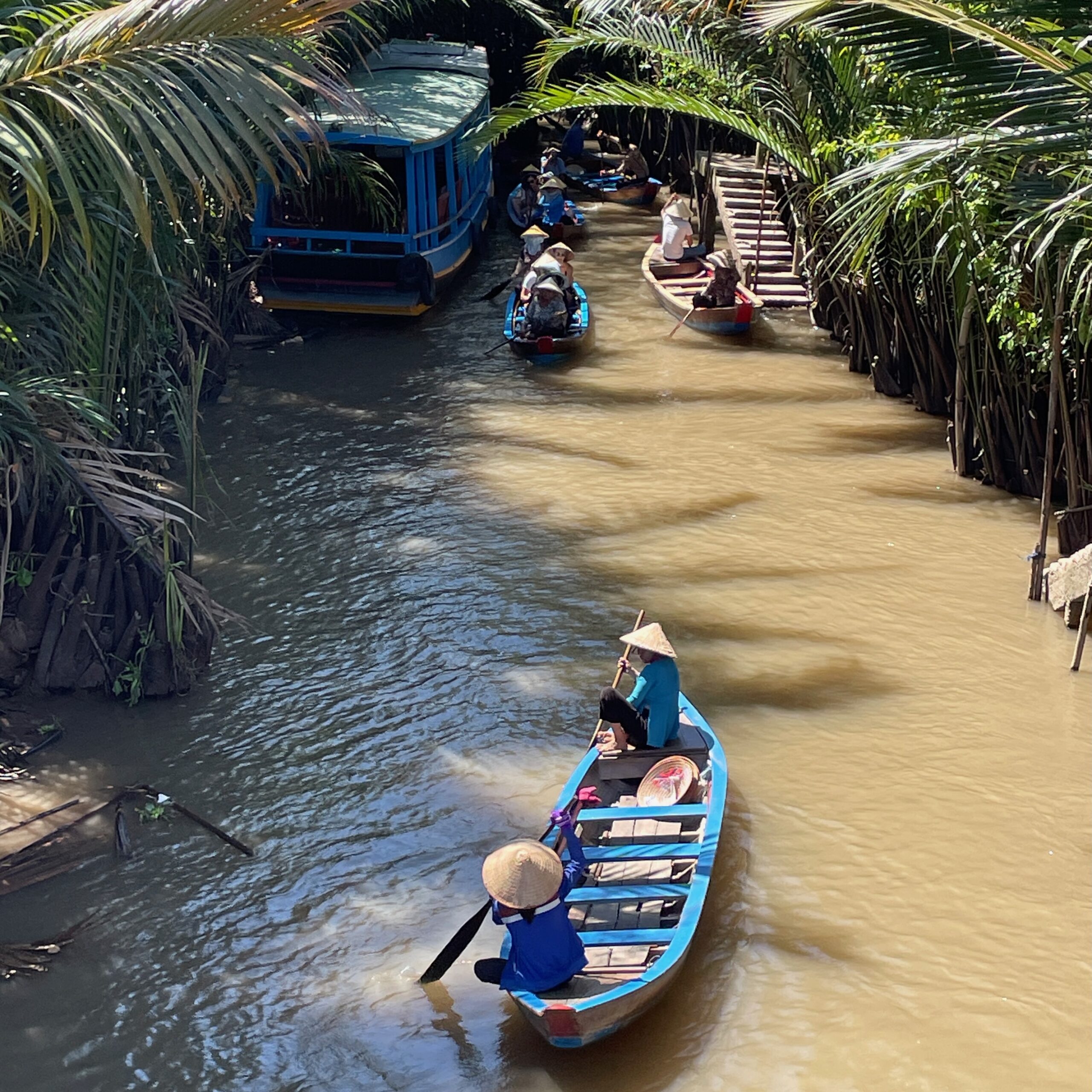 two Vietnamese local women canoeing along the Mekong Delta River in Vietnam on a sunny day
