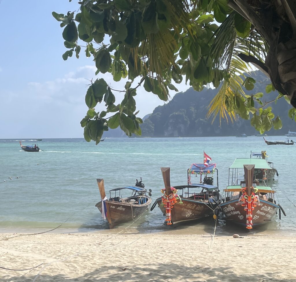 Longtail boats on a tropical Thai beach, used to promote a Thailand travel webinar offering expert trip planning advice.
