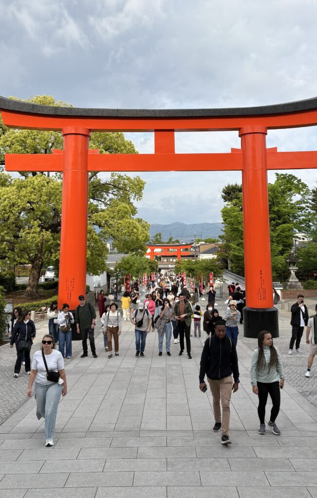 Tourists walking toward Kyoto’s iconic red temple at 7 AM, with soft morning light and peaceful surroundings.
