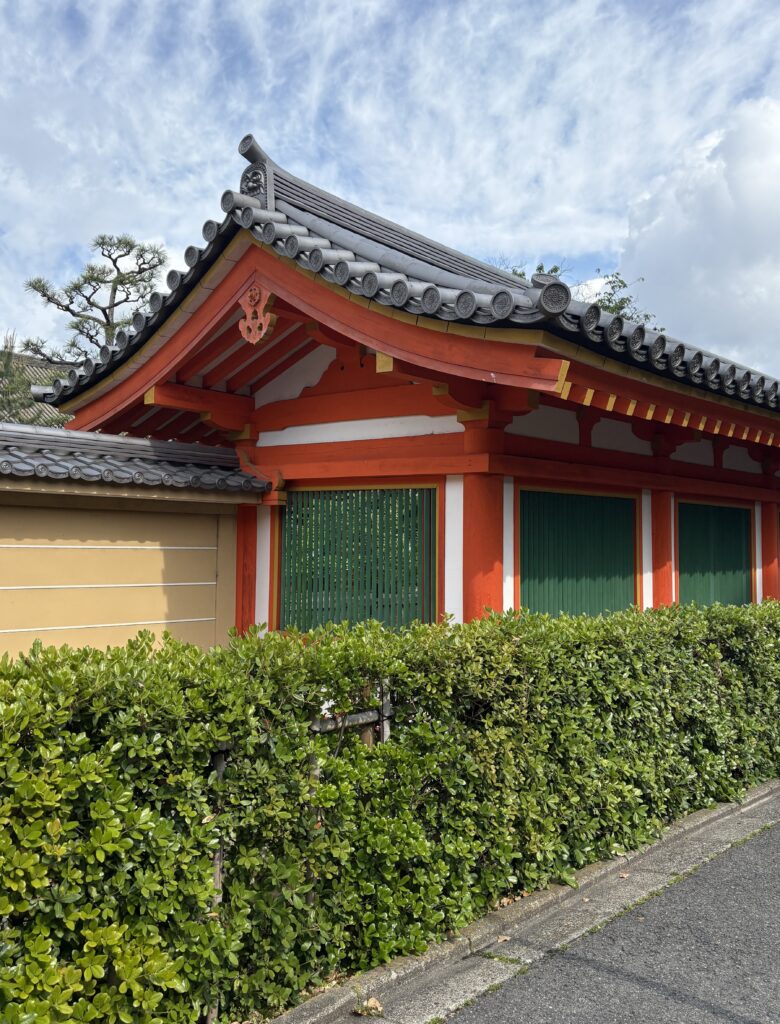 Traditional Japanese temple with bright orange roofing under a clear blue sky in Kyoto.