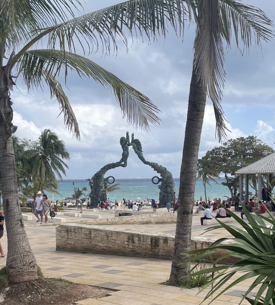 Locals and tourists gathered around the famous mermaid statue in Playa del Carmen near the beachfront, a central landmark in the town.