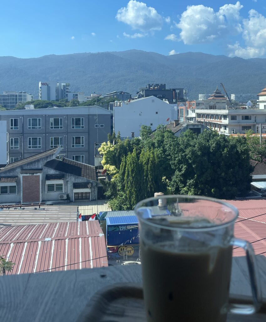 A cup of coffee with a stunning mountain view under a clear midday sky in Chiang Mai, Thailand.
