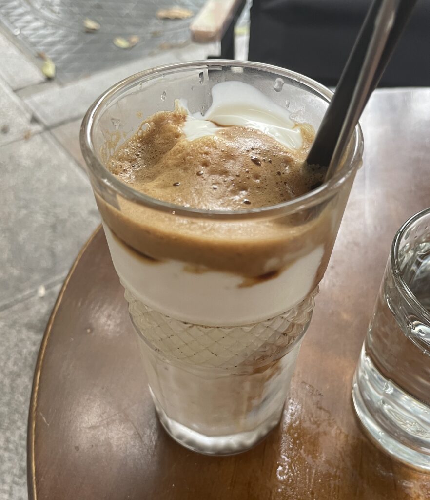 A glass of Vietnamese yogurt coffee served with water at a streetside café in Hanoi on a quiet morning