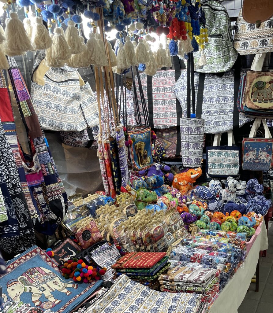 An array of elephant-themed souvenirs, including figurines and trinkets, displayed at a market in Thailand.