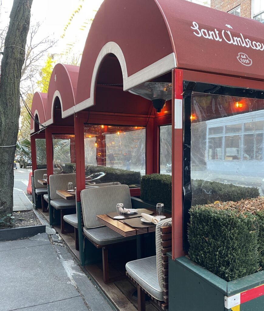 Empty street-side restaurant in New York City decorated for Christmas in the early evening.
