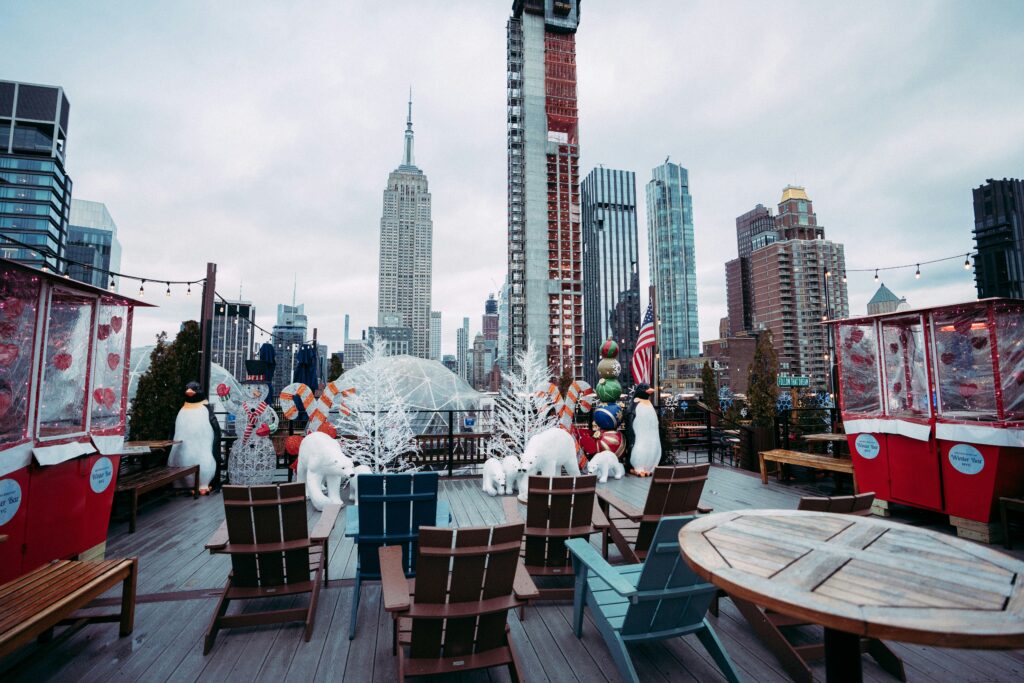 Empty rooftop in New York City decorated with Christmas lights and holiday decor.
