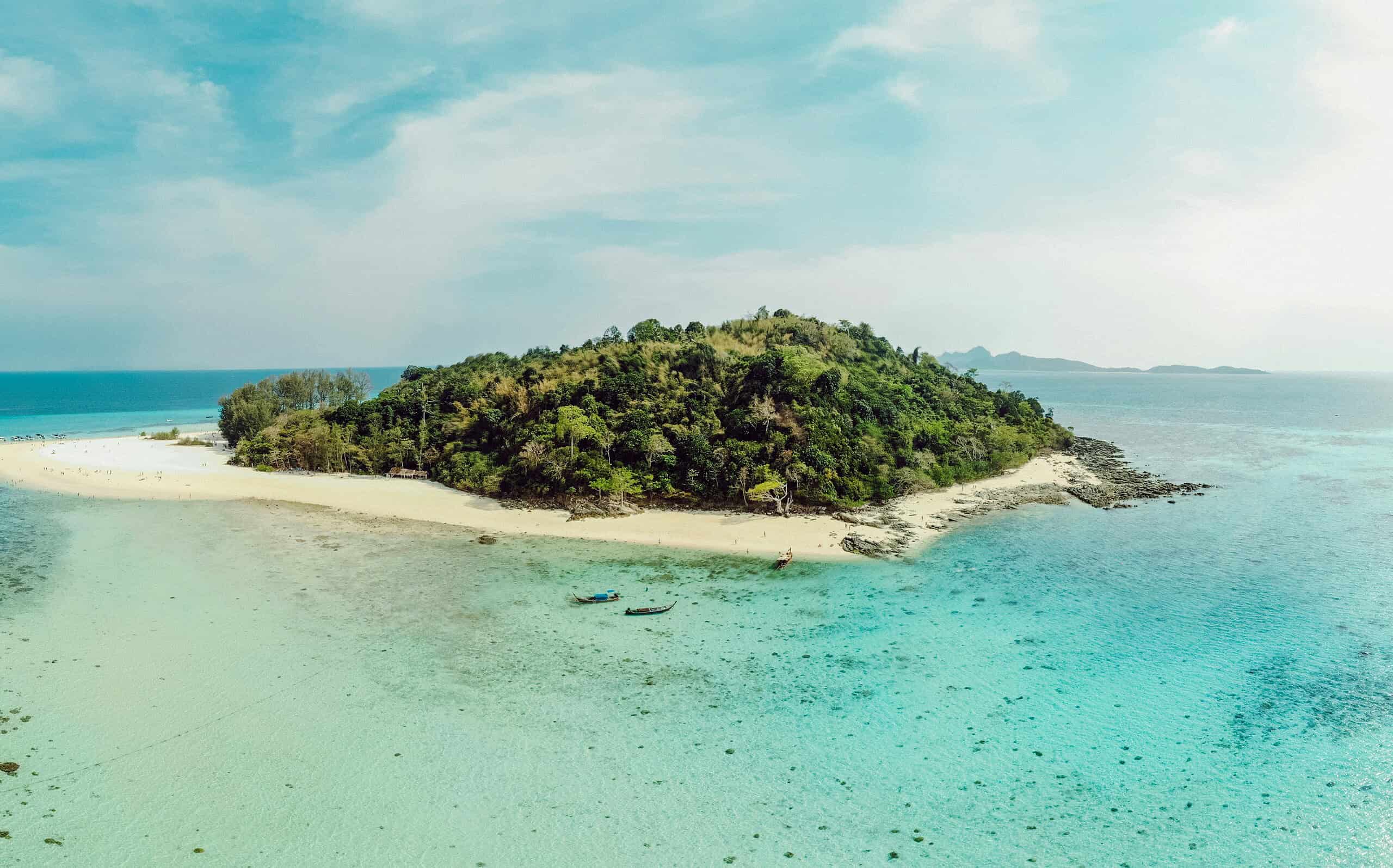 Aerial view of Bamboo Island in the Phi Phi Islands, showing turquoise waters, soft white sand, and lush greenery surrounded by the Andaman Sea.
