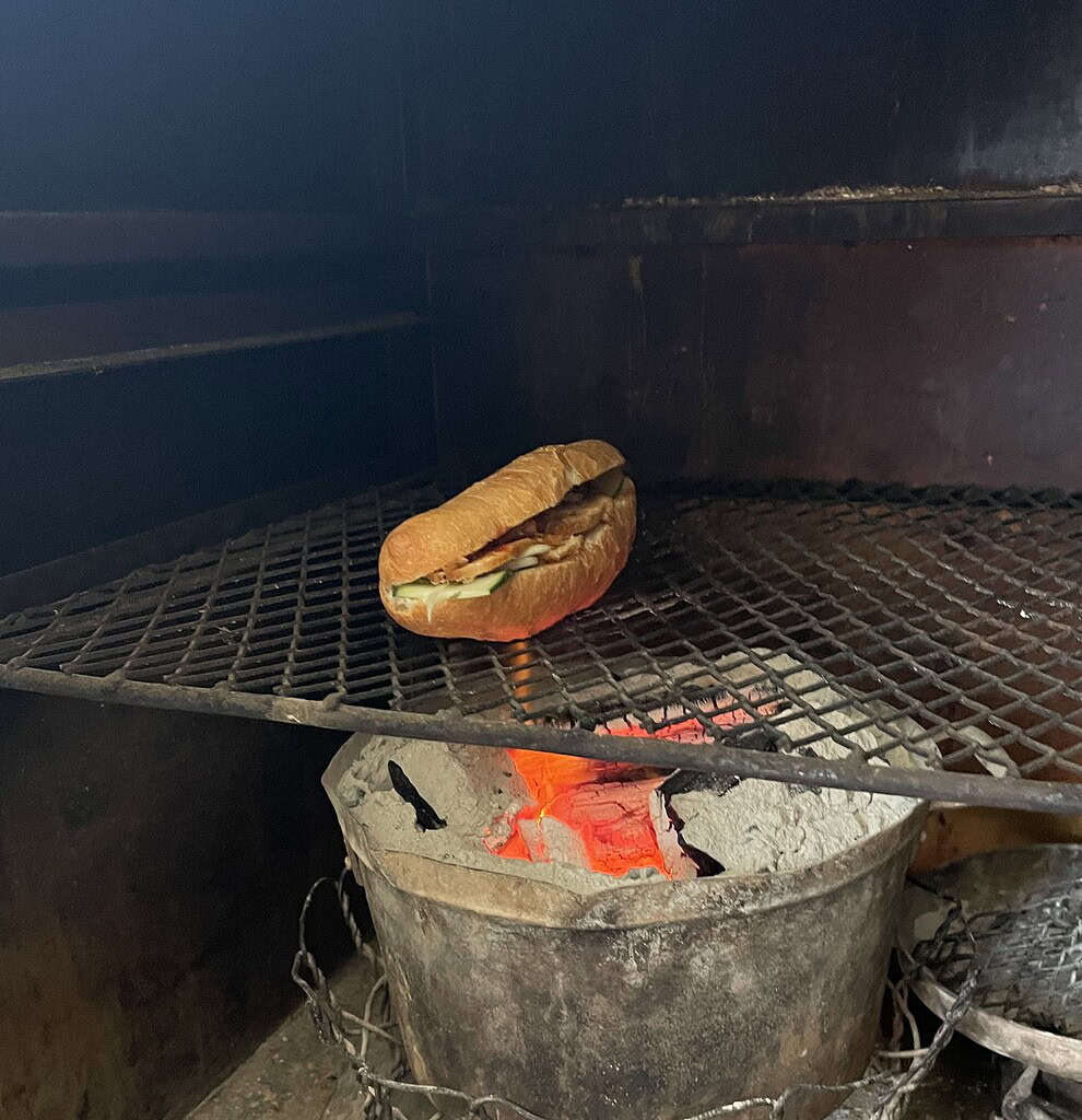 Banh mi being toasted over hot charcoal at Phi Banh Mi shop in Hoi An.