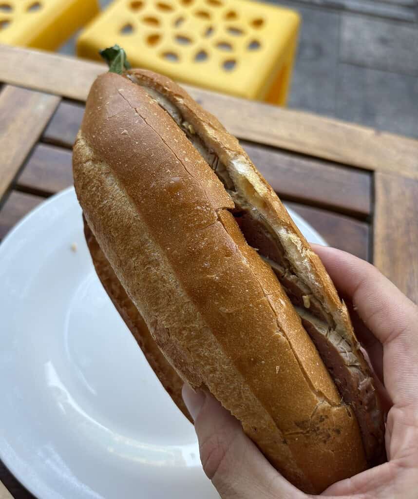 Close-up of a perfectly crisp banh mi in Saigon, filled with cold cuts and various traditional Vietnamese toppings.