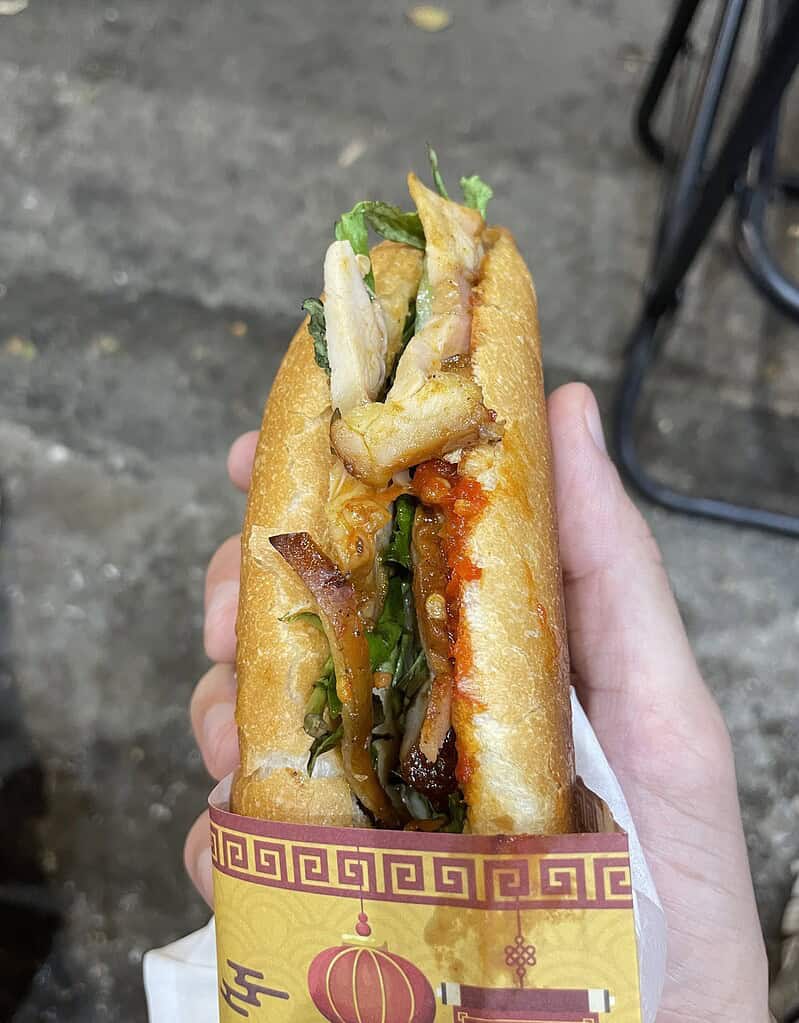Hoi An-style chicken banh mi served in Hanoi, showing the full sandwich with crisp bread and fresh toppings.
