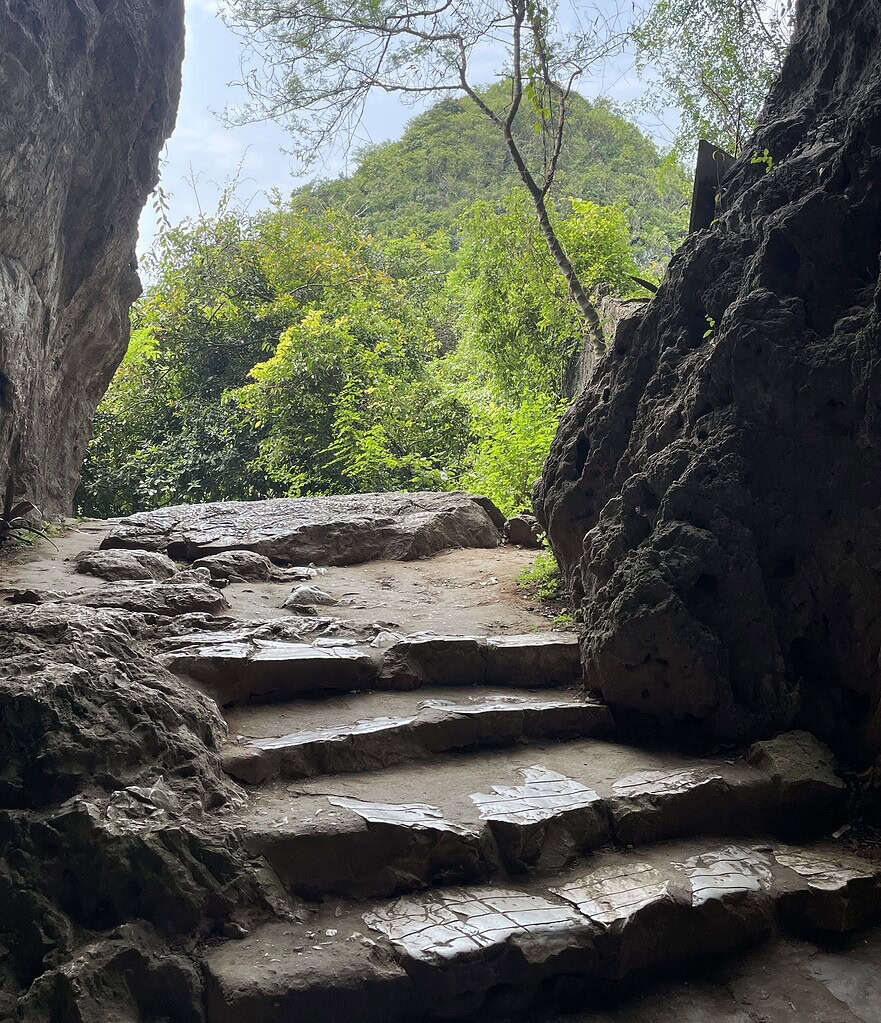 View from inside a cave at the Marble Mountains in Da Nang, looking out toward a stone stairway with sweeping views of the city ahead.