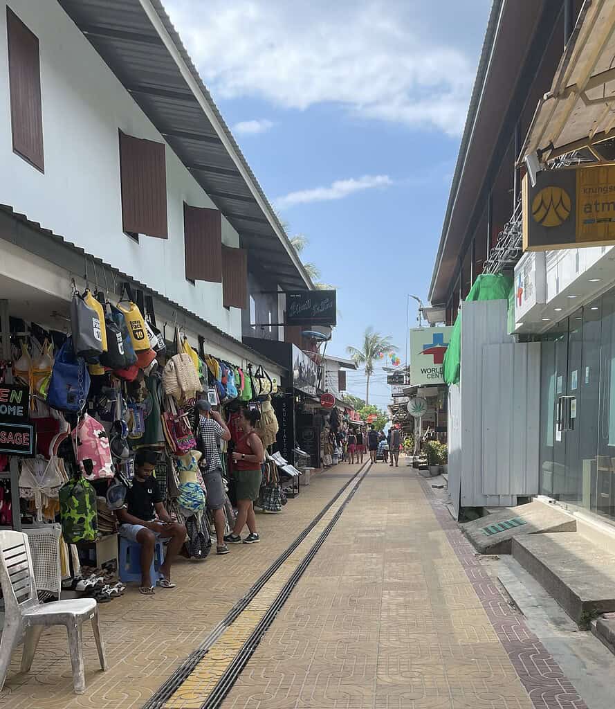 Walkway through Tonsai Market in Phi Phi Island with shops selling beach bags, swimsuits, and local souvenirs.