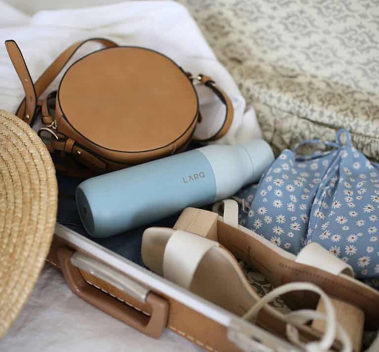 Clothing, shoes, and personal items being packed into a suitcase for a New York City trip