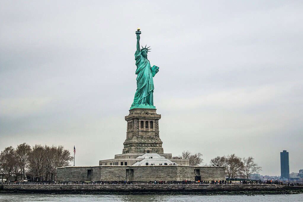 Close-up of the Statue of Liberty in New York City, capturing the iconic crown and torch against a cloudy sky.